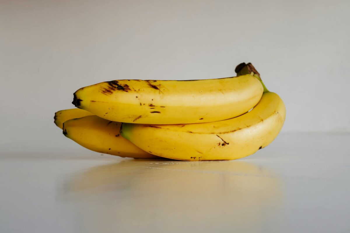 A bunch of fresh yellow bananas stacked elegantly on a smooth white surface, ready to eat.