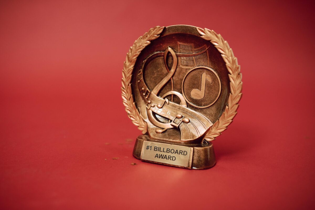 A close-up of a golden music award trophy against a vibrant red background.