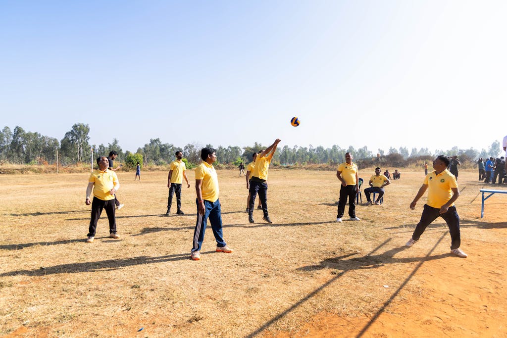 A group of people playing volleyball on a sunny outdoor field.