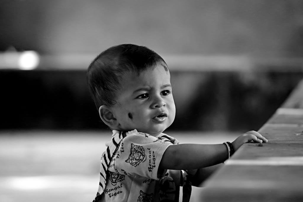 Adorable black and white portrait of a curious baby indoors, capturing innocence and wonder.