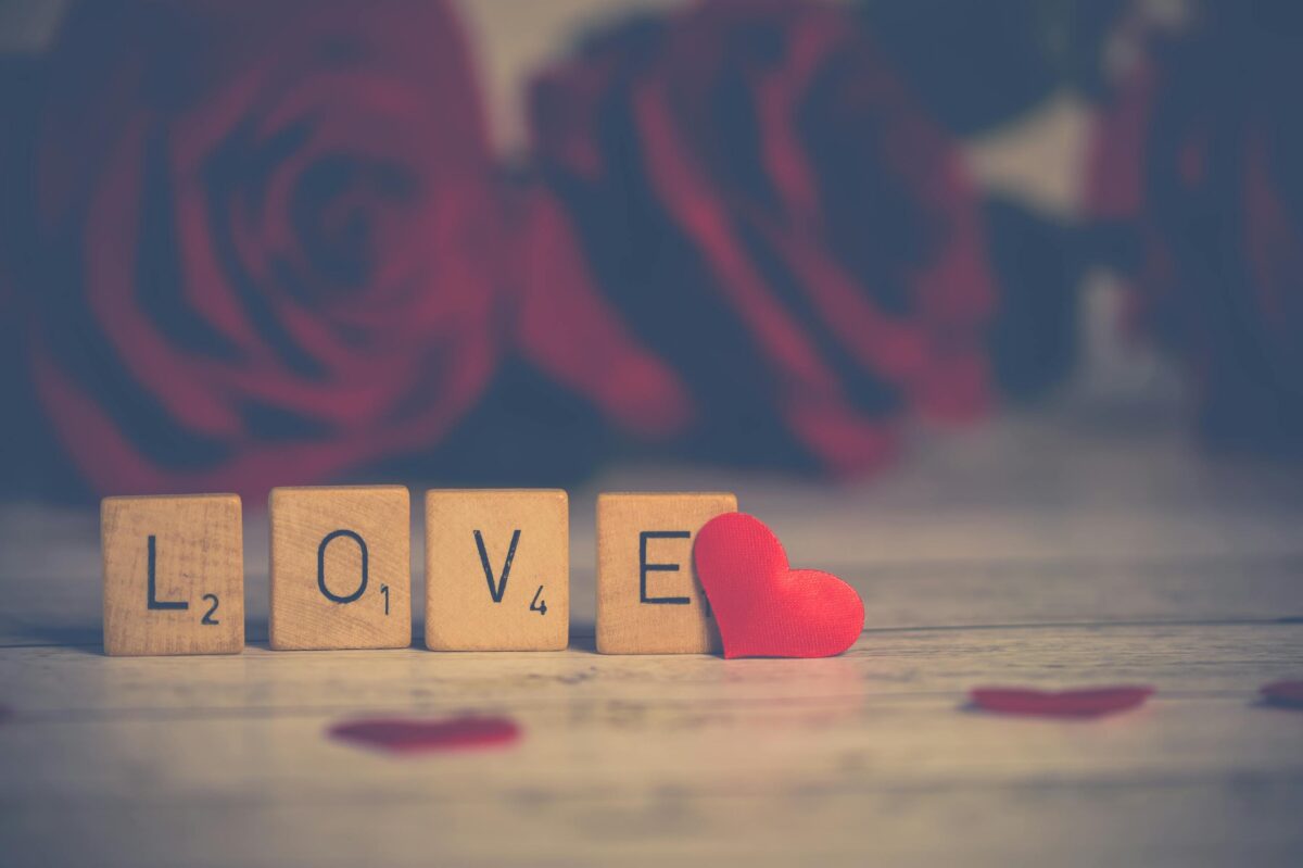 Scrabble tiles spelling 'LOVE' with red roses, perfect for Valentine's Day.